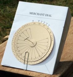 a wooden table with a paper clock on it's side and the words merchant dial written in white