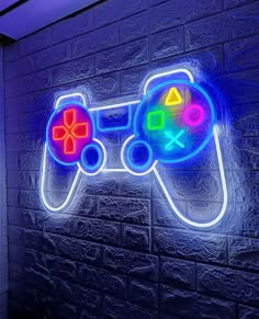 a neon video game controller sign on the side of a brick wall in a dark room