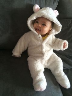 a baby in a white bear costume sitting on a couch