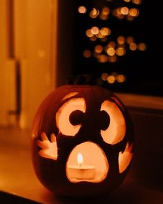 a carved pumpkin sitting on top of a window sill with a lit candle in it