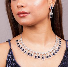 Sapphire Diamond Necklace Set features a stunning blue stone centerpiece surrounded by sparkling CZ American diamonds. The set includes a matching ring, making it a perfect statement piece for a contemporary Indian bride. Ideal as a wedding gift, it exudes elegance and modern sophistication. *𝐏𝐑𝐎𝐃𝐔𝐂𝐓 𝐃𝐄𝐓𝐀𝐈𝐋* * 𝐌𝐚𝐭𝐞𝐫𝐢𝐚𝐥: Brass * 𝐏𝐥𝐚𝐭𝐢𝐧𝐠: White Rhodium Plated * 𝐒𝐭𝐨𝐧𝐞: AAA-quality CZ Diamond & Sapphire. *𝐃𝐈𝐌𝐄𝐍𝐒𝐈𝐎𝐍𝐒* *𝐍𝐞𝐜𝐤𝐥𝐚𝐜𝐞* * 𝐖𝐞𝐢𝐠𝐡𝐭: 56 gm  * 𝐃𝐫𝐨𝐩  𝐋𝐞𝐧𝐠𝐭𝐡: 4.7 Inches * 𝐋𝐞𝐧𝐠𝐭𝐡: 9 Inches * 𝐖𝐢𝐝𝐭𝐡:  1.1 Inches *𝐄𝐚𝐫𝐫𝐢𝐧𝐠𝐬* * 𝐖𝐞𝐢𝐠𝐡𝐭: 8 gm each * 𝐋𝐞𝐧𝐠𝐭𝐡: 1.85 Inches * 𝐖𝐢𝐝𝐭𝐡:  0.55 Inches * 𝐂𝐥𝐨𝐬𝐮𝐫𝐞: Push Back 𝐕𝐢𝐬𝐢𝐭 𝐎𝐮𝐫 𝐅𝐀𝐐𝐬 𝐟𝐨𝐫 𝐒𝐡𝐢𝐩𝐩𝐢𝐧𝐠 𝐏𝐨𝐥𝐢𝐜𝐢𝐞𝐬 𝐚𝐧𝐝 𝐂𝐚𝐫? Cubic Zirconia Gemstone Jewelry For Reception, Blue Cubic Zirconia Jewelry For Party, Sapphire Crystal Jewelry For Anniversary, Blue Cubic Zirconia Party Jewelry, Elegant Blue Necklace For Receptions, Elegant Blue Necklace For Reception, Elegant Blue Bridal Sets Gift, Sapphire Cubic Zirconia Jewelry Set For Party, Blue Gemstone Jewelry Sets For Wedding