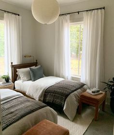 two beds in a bedroom with white curtains