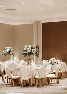 the tables are set with white flowers in vases and centerpieces on them