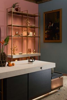 a kitchen with pink walls and shelves filled with pots, vases and other items