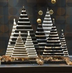 three wooden christmas trees are on display in a window