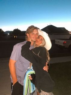 a man and woman standing next to each other in front of a house at night