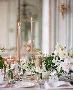 the table is set with candles, flowers and place settings for an elegant dinner party