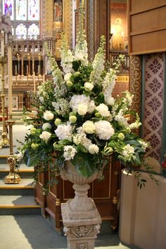 white flowers in a urn at the alter of a church