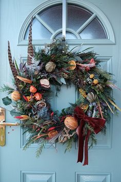 a wreath on the front door is adorned with feathers and foliage