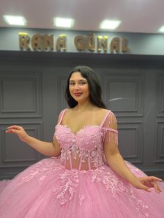 a woman in a pink ball gown posing for the camera with her hands out and arms outstretched