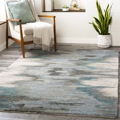 a living room area with a chair, rug and potted plant on the floor