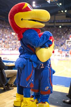 the mascot is hugging his friend on the court