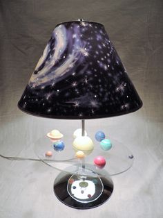 a lamp that is sitting on top of a glass base with planets and stars painted on it