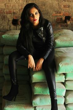 a woman sitting on top of a pile of sandbags in front of a brick wall