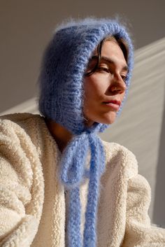 The Brushed Mohair Bonnet is your fluffy new best friend. Hand-knit in our signature super soft mohair, it delivers warmth and comfort while offering a playful twist to classic headwear. Its long, textured ribbons allow you to tie it either at the front or at the back, giving you styling flexibility to suit any look or mood. Wear it snug for full coverage or draped loosely as a hood for a more relaxed vibe. Handcrafted in Greece. DETAILS * Super soft, premium quality Italian mohair * 60% kid moh Hood Scarf Knitting Pattern, Mohair Projects, Knitting Bonnet, Balaclava Knitted, Bonnet Outfit, Mohair Shrug, Mohair Bonnet, Balaclava Knit, Cute Winter Hat