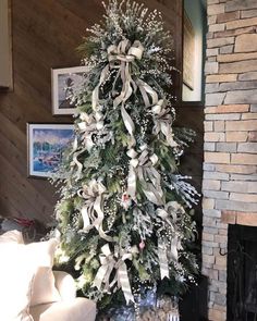 a decorated christmas tree in a living room with white and silver decorations on the top