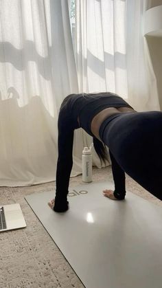 a woman is doing yoga in front of a laptop