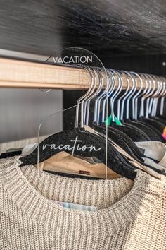 a sweater hanging on a hanger in a closet with vacation written on the label