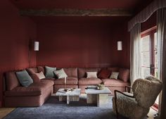 a living room with red walls and furniture in the corner, including a large sectional couch