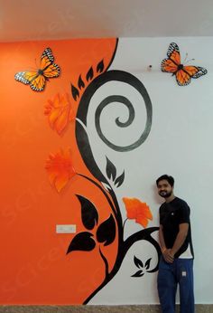 a man standing in front of a wall with butterflies on it and an orange background