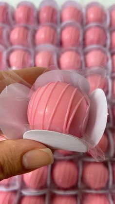 a hand holding a pink heart shaped chocolate in a plastic container filled with candy balls