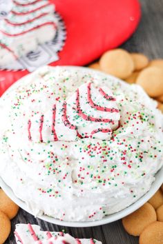 a cake with white frosting and sprinkles sitting on top of cookies