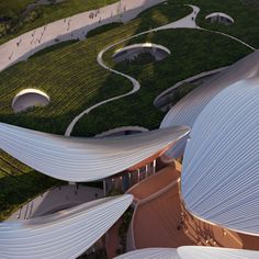 an aerial view of a building with green roofing and curved walkways on the side