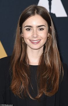 a woman with long brown hair smiling at the camera and wearing a black suit jacket