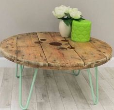 a wooden table with two green vases sitting on it's legs next to a white flower