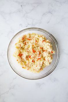 a bowl filled with rice and carrots on top of a white countertop next to a knife