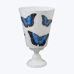 a white vase with blue butterflies painted on the side and bottom, sitting in front of a white background