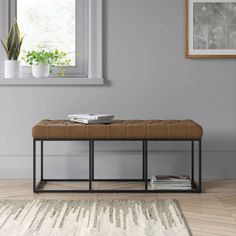 a bench in front of a window with potted plants on the floor and a rug underneath it