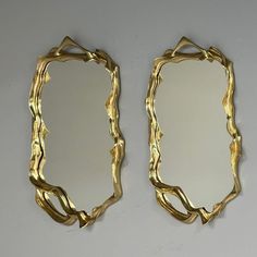 two mirrors that are next to each other on a wall, one is made out of gold leafy branches