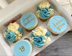 the cupcakes are decorated with blue and white icing, roses and leaves