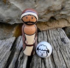 a wooden figurine next to a painted egg on a wood planked surface