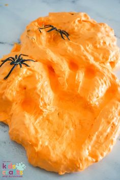 an orange cake with black spider decorations on it's icing, sitting on a marble surface