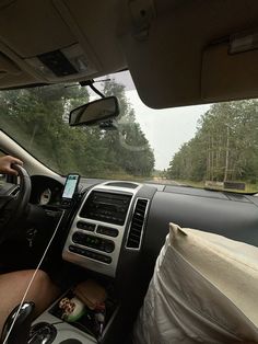 a man driving a car on a road with trees in the background