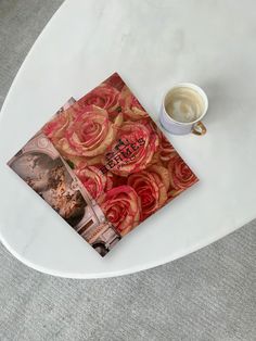 a cup of coffee sitting on top of a white table next to a napkin with red roses