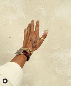 a woman's hand with a bird tattoo on her left wrist and gold bracelet