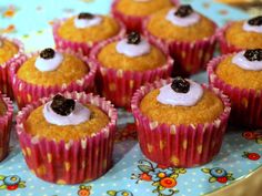 small cupcakes with icing and blackberries on top sitting on a plate