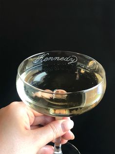 a person holding a wine glass in their hand with the word henness written on it