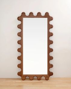 a mirror sitting on top of a wooden table next to a white wall and wood floor