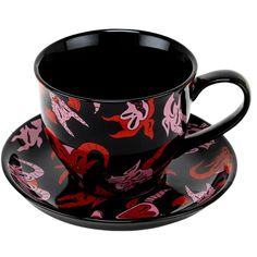 a black cup and saucer with red designs on it