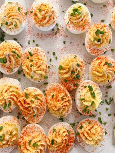 several deviled eggs with sprinkles and green garnish on top