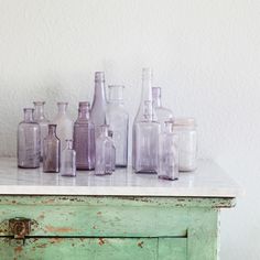 an old dresser with bottles and jars on it, in shades of purple and green