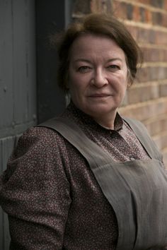 a woman standing in front of a brick wall with her hands on her hips and looking at the camera