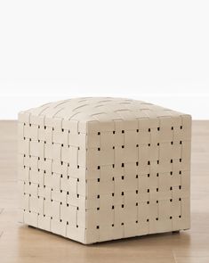 an ottoman made out of cardboard with black squares on the top and bottom, sitting on a hard wood floor