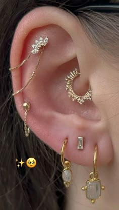 a woman wearing three different types of ear piercings