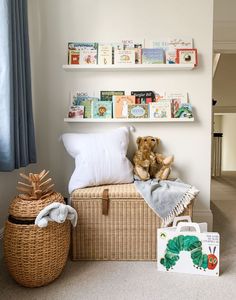 a stuffed animal sitting on top of a trunk next to bookshelves and pillows