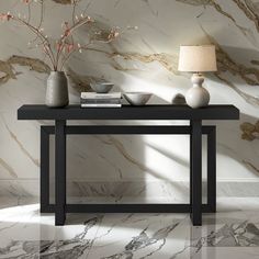 a table with two vases on it next to a lamp and some books in front of a marble wall